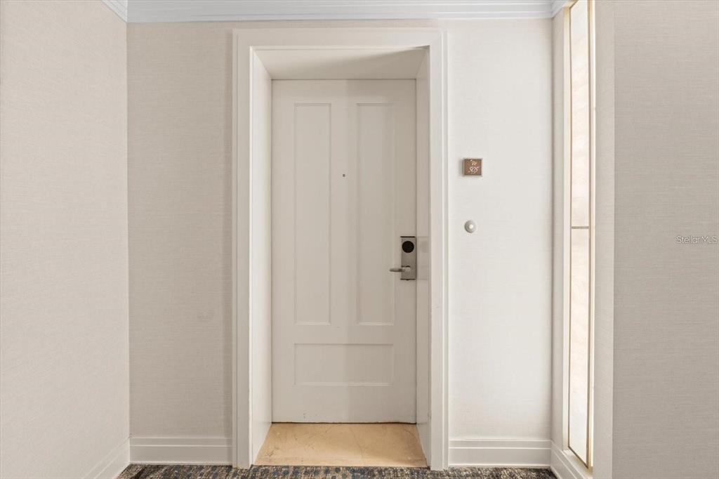 A white door with a room number plaque is centered in a neutral-toned hallway — 915 SEASIDE DR UNIT 405, WEEKS 22-23, SARASOTA, FL