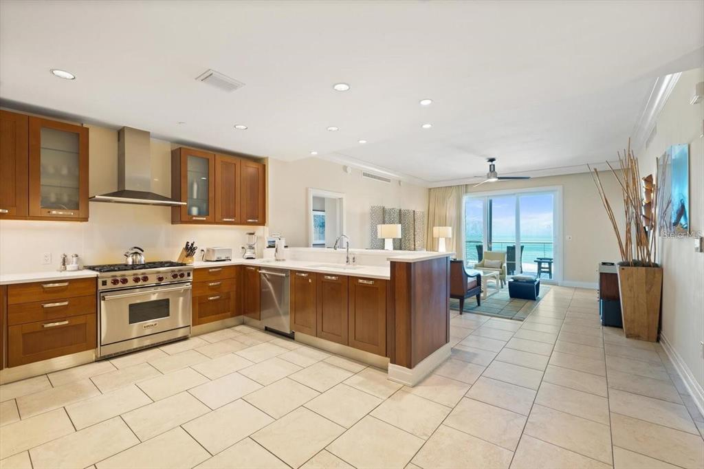 A kitchen with wood cabinets and stainless steel appliances opens to a living area with ocean views — 915 SEASIDE DR UNIT 405, WEEKS 22-23, SARASOTA, FL