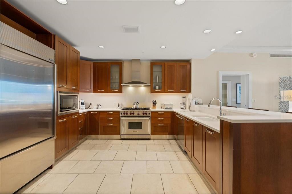 A kitchen features wood cabinetry, stainless steel appliances, and light-colored tile flooring — 915 SEASIDE DR UNIT 405, WEEKS 22-23, SARASOTA, FL