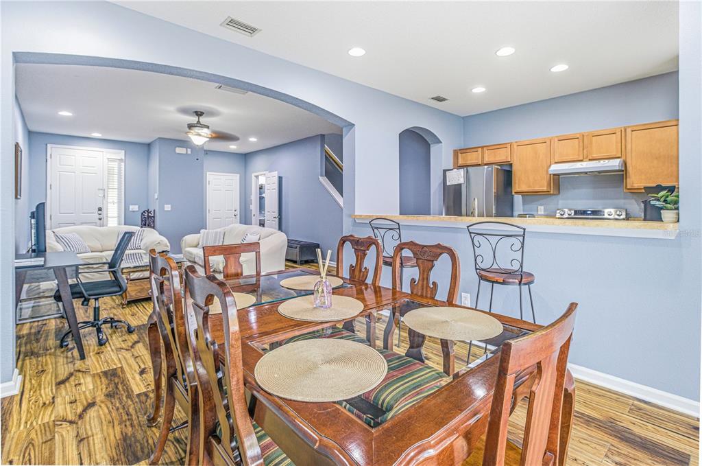 A dining area with a wooden table and chairs sits before an open-concept kitchen — 3690 CRESWICK CIRCLE UNIT B, ORANGE PARK, FL