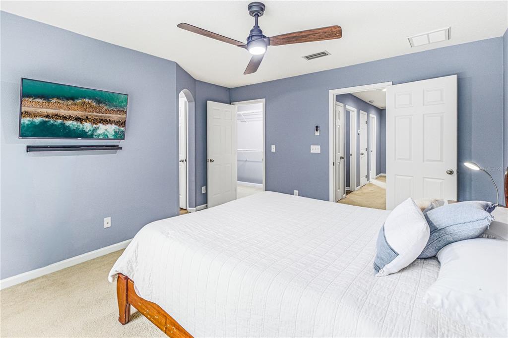 A bedroom with blue walls, a ceiling fan, a wall-mounted television, and an open closet — 3690 CRESWICK CIRCLE UNIT B, ORANGE PARK, FL