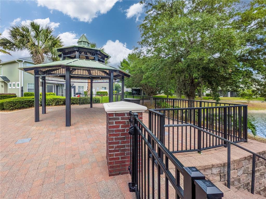 A gazebo with a green metal roof stands on a brick patio near a pond — 3690 CRESWICK CIRCLE UNIT B, ORANGE PARK, FL