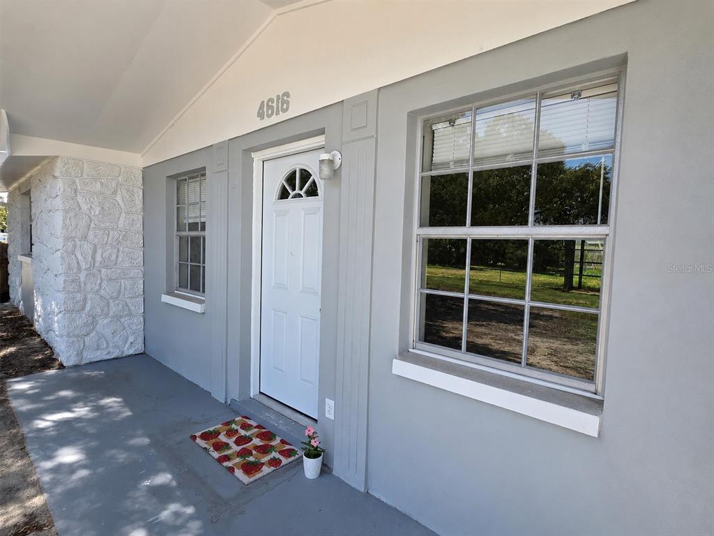 A gray exterior wall features a white front door, two windows, and stone siding — 4616 IRENE LOOP, NEW PORT RICHEY, FL