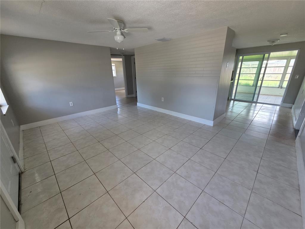 An open-concept living area features light gray walls, white tile flooring, and a ceiling fan — 4616 IRENE LOOP, NEW PORT RICHEY, FL