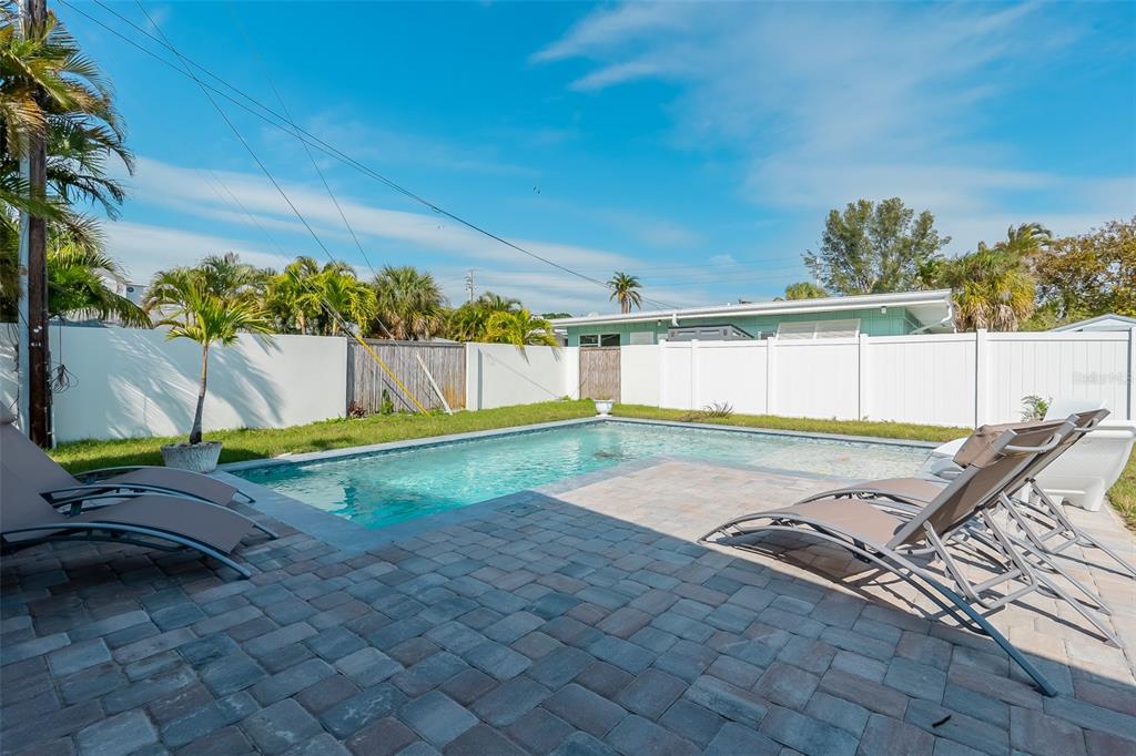 A backyard features a rectangular swimming pool, a paver patio, and lounge chairs — 408 71ST STREET, HOLMES BEACH, FL