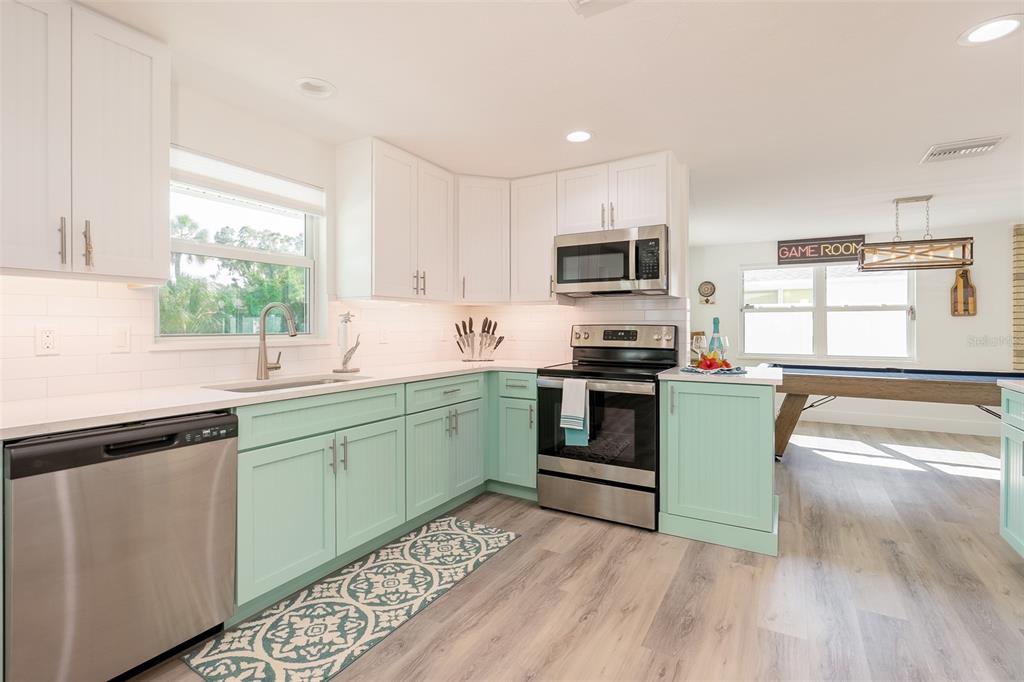 A kitchen features mint green lower cabinets, white upper cabinets, and stainless steel appliances — 408 71ST STREET, HOLMES BEACH, FL