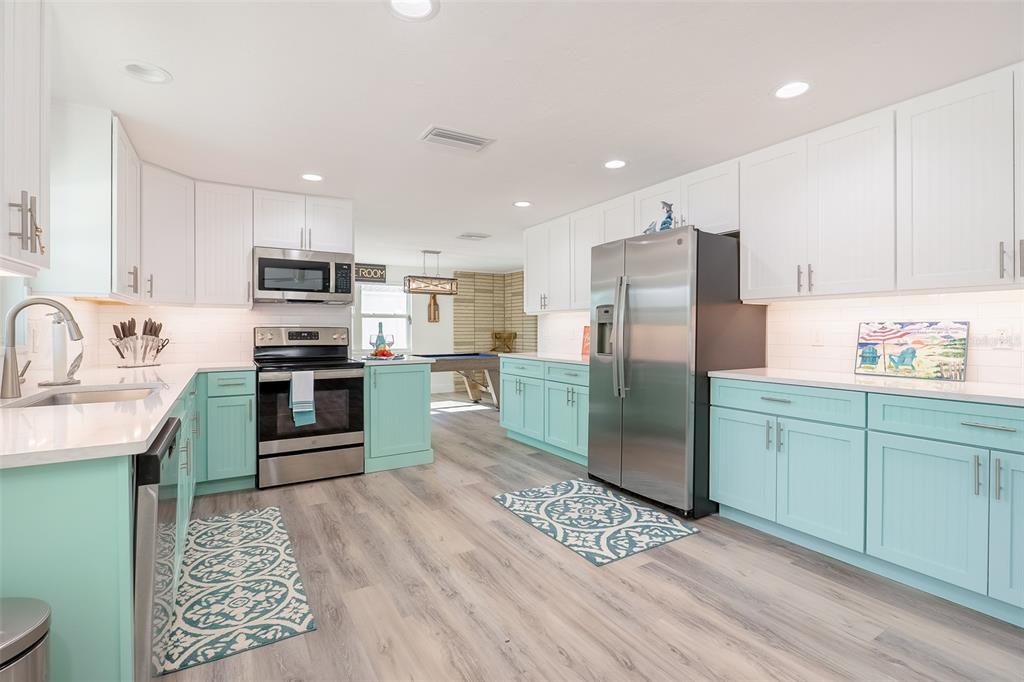 A kitchen features white upper cabinets, light blue lower cabinets, stainless steel appliances, and wood-look flooring — 408 71ST STREET, HOLMES BEACH, FL