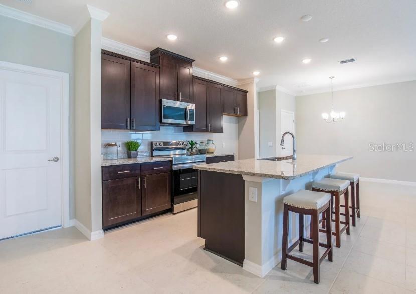 A kitchen features dark wood cabinets, granite countertops, a center island, and three bar stools — 39 POPLAR DRIVE, PALM COAST, FL