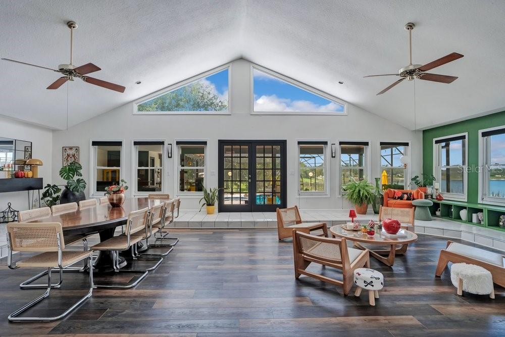 A spacious open-concept living and dining room with vaulted ceilings, large windows, and dark flooring — 8142 CHIANTI DRIVE, ORLANDO, FL