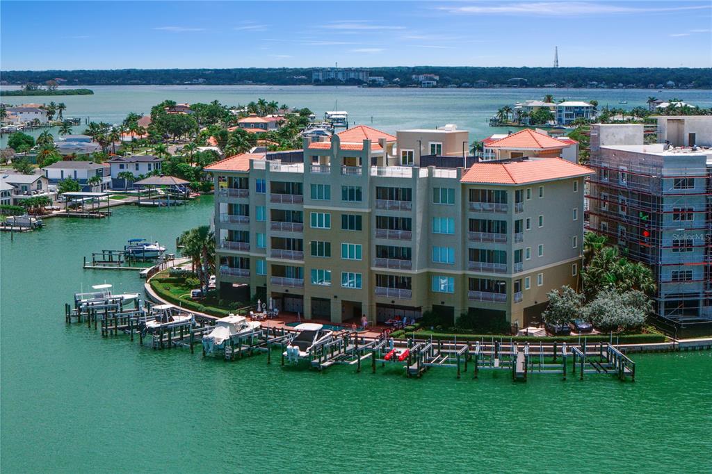 An aerial view of a multi-story waterfront condominium building with boat slips and a pool — 200 SKIFF POINT UNIT 501, CLEARWATER BEACH, FL