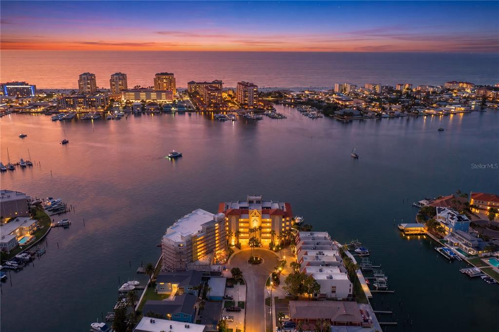 An aerial view of a waterfront condominium complex at sunset with boats in the harbor — 200 SKIFF POINT UNIT 501, CLEARWATER BEACH, FL