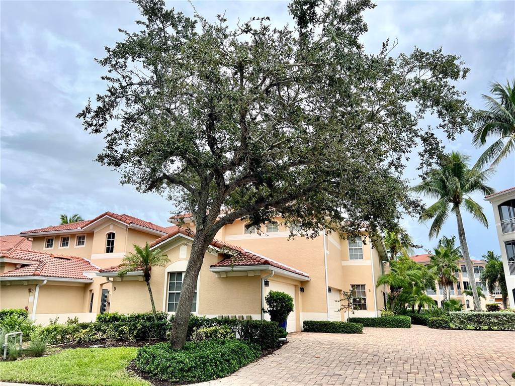A large tree stands in front of a two-story tan stucco house with a tiled roof — 3304 SUNSET KEY CIRCLE UNIT D, PUNTA GORDA, FL