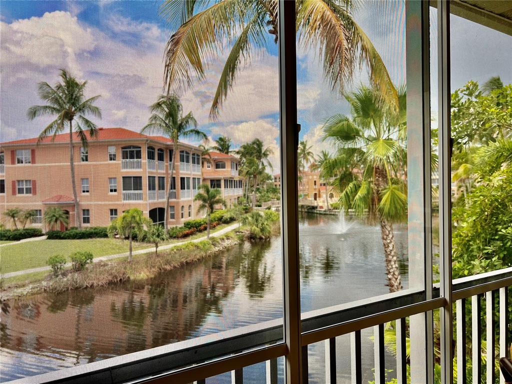 A view of a canal, palm trees, and apartment buildings from a screened-in balcony — 3304 SUNSET KEY CIRCLE UNIT D, PUNTA GORDA, FL