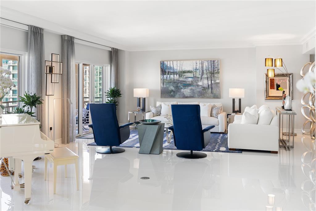 A bright living room features white sofas, blue accent chairs, a glass coffee table, and balcony — 1111 RITZ CARLTON DRIVE UNIT 1603, SARASOTA, FL