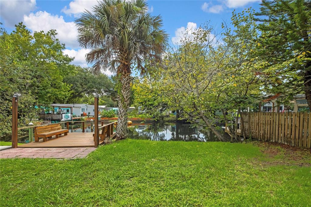 A wooden dock with a bench sits beside a canal surrounded by trees and grass — 5610 RAMADA STREET, WEEKI WACHEE, FL