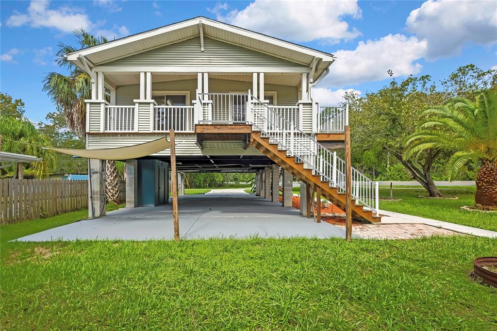 An elevated house with a covered ground-level parking area and a wooden staircase leading upstairs — 5610 RAMADA STREET, WEEKI WACHEE, FL