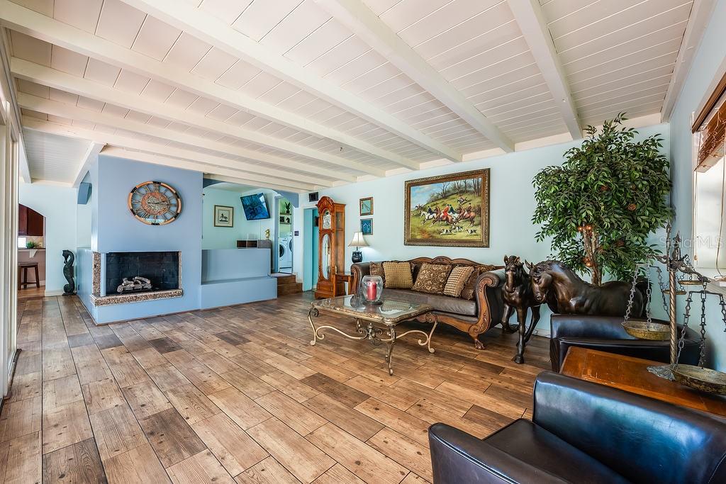 A living room with wood-look tile floors, a fireplace, and a vaulted beamed ceiling — 1835 OAK LANE, ORLANDO, FL