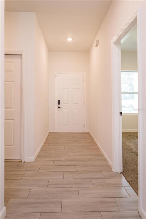 A hallway with light-colored tile flooring leads to a white front door — 1022 36TH, ORLANDO, FL