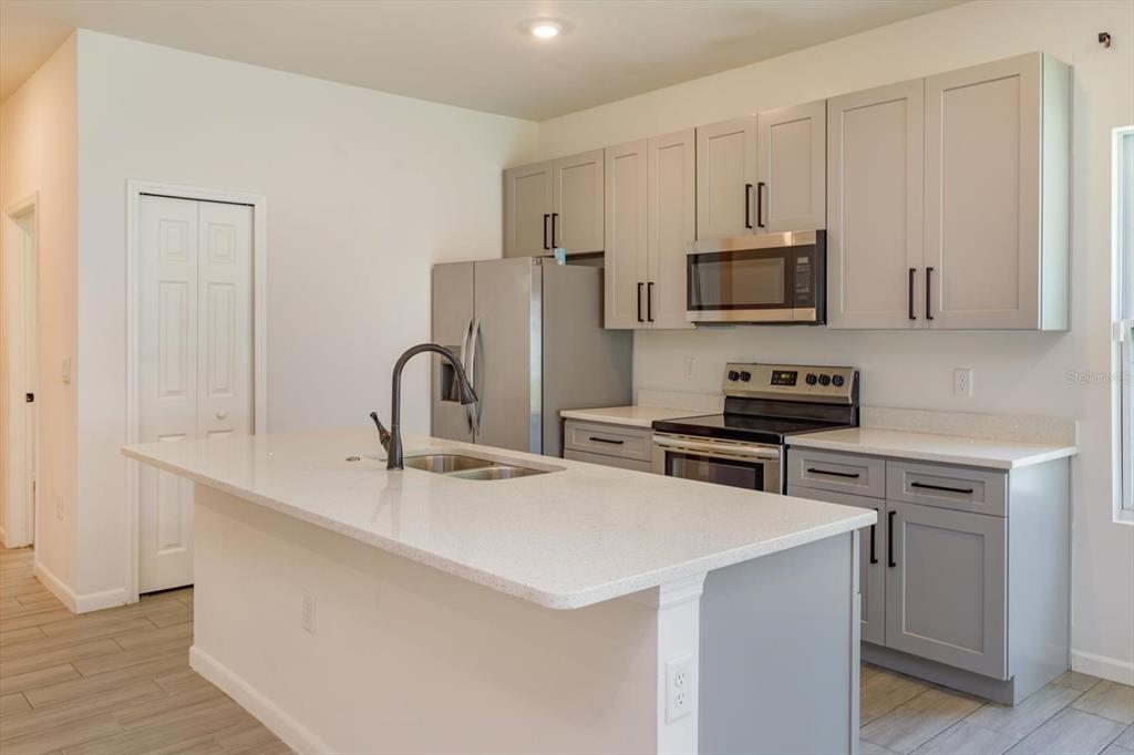 A kitchen features gray cabinets, stainless steel appliances, and a white quartz-topped island — 1022 36TH, ORLANDO, FL