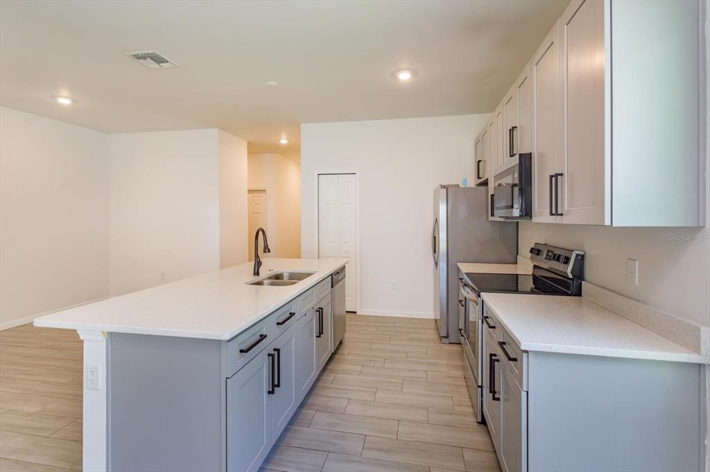 A kitchen features a gray island with a sink, white countertops, and light-colored cabinetry — 1022 36TH, ORLANDO, FL