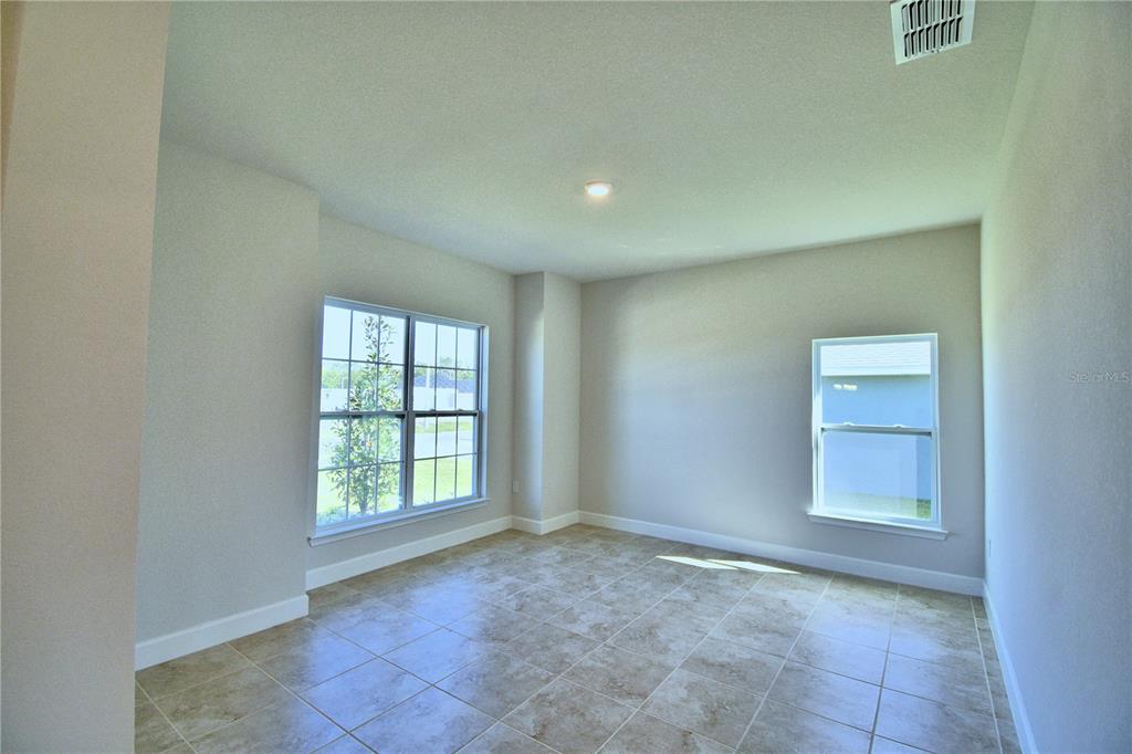 An empty room features light-colored walls, tiled flooring, and two windows — 4425 JUNEBERRY DRIVE, AUBURNDALE, FL