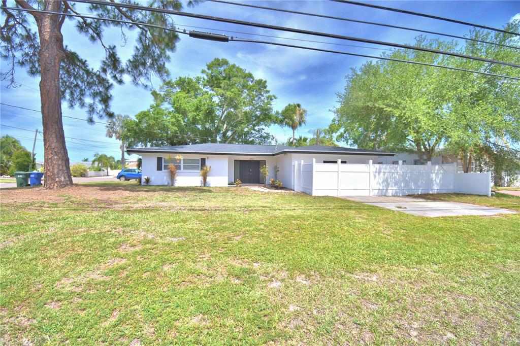 A white single-story house with a concrete driveway and a large pine tree in front — 3553 CENTER CIRCLE, LARGO, FL
