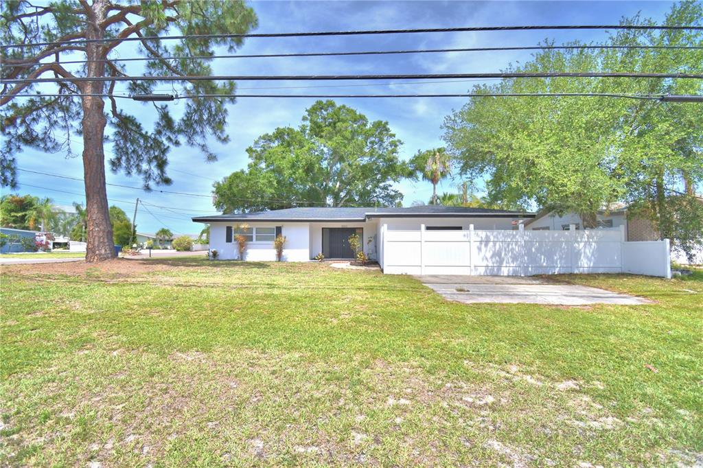 A white house exterior features a concrete driveway, a sunroom, and a dark entry door — 3553 CENTER CIRCLE, LARGO, FL