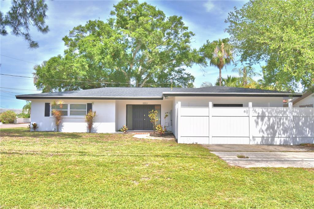 A white single-story house features a large glass-enclosed porch and a concrete driveway — 3553 CENTER CIRCLE, LARGO, FL