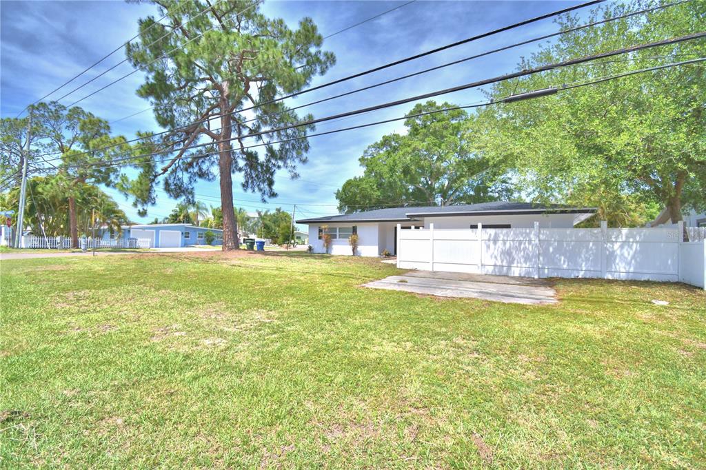 A white house exterior features a concrete driveway, a sunroom, and a dark entry door — 3553 CENTER CIRCLE, LARGO, FL