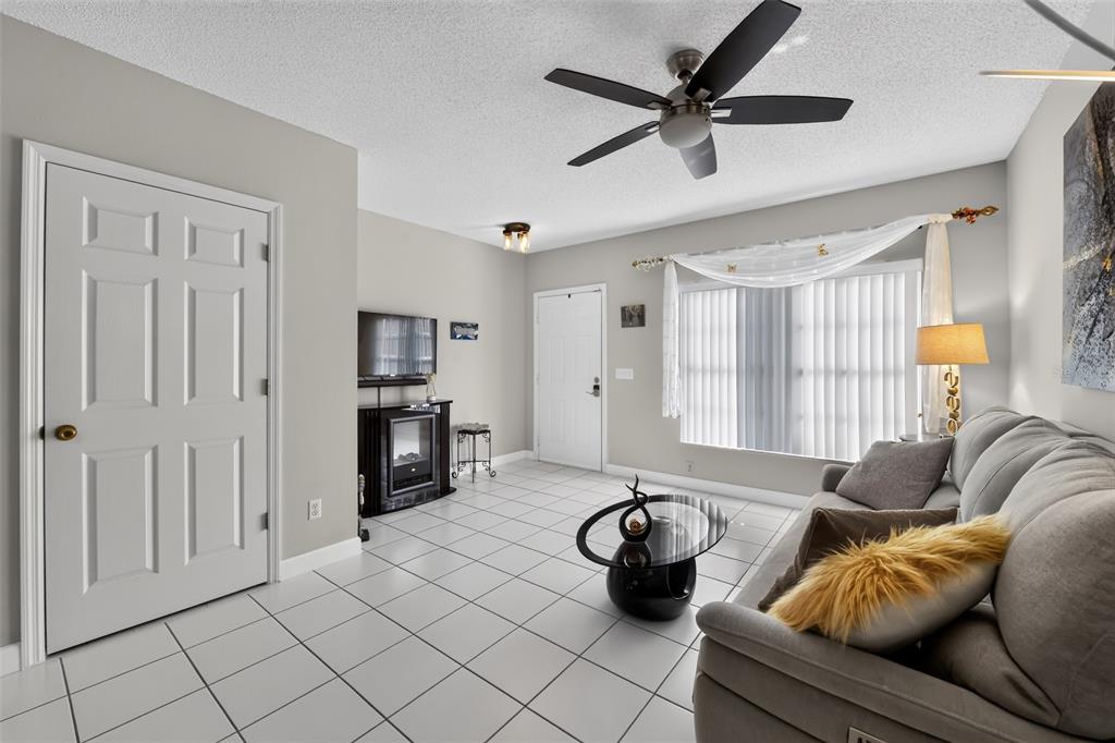 A living room with white tile floors, a grey sofa, and a ceiling fan — 4725 SABAL KEY DRIVE, BRADENTON, FL