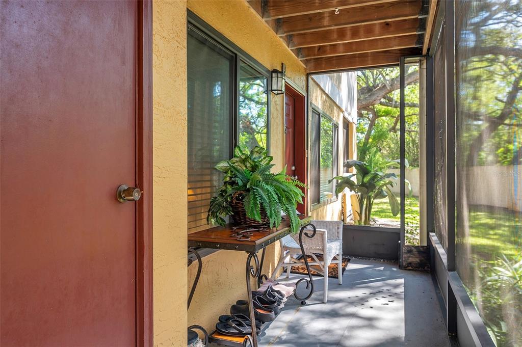 A screened-in porch with a yellow wall, a console table, and a white wicker chair — 1550 S BELCHER ROAD UNIT 117, CLEARWATER, FL