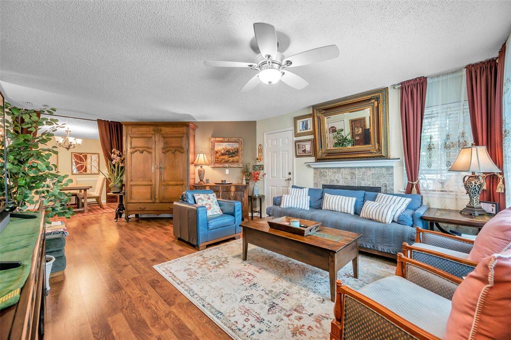 A living room features a blue sofa, armchairs, a wooden coffee table, and a ceiling fan — 1550 S BELCHER ROAD UNIT 117, CLEARWATER, FL
