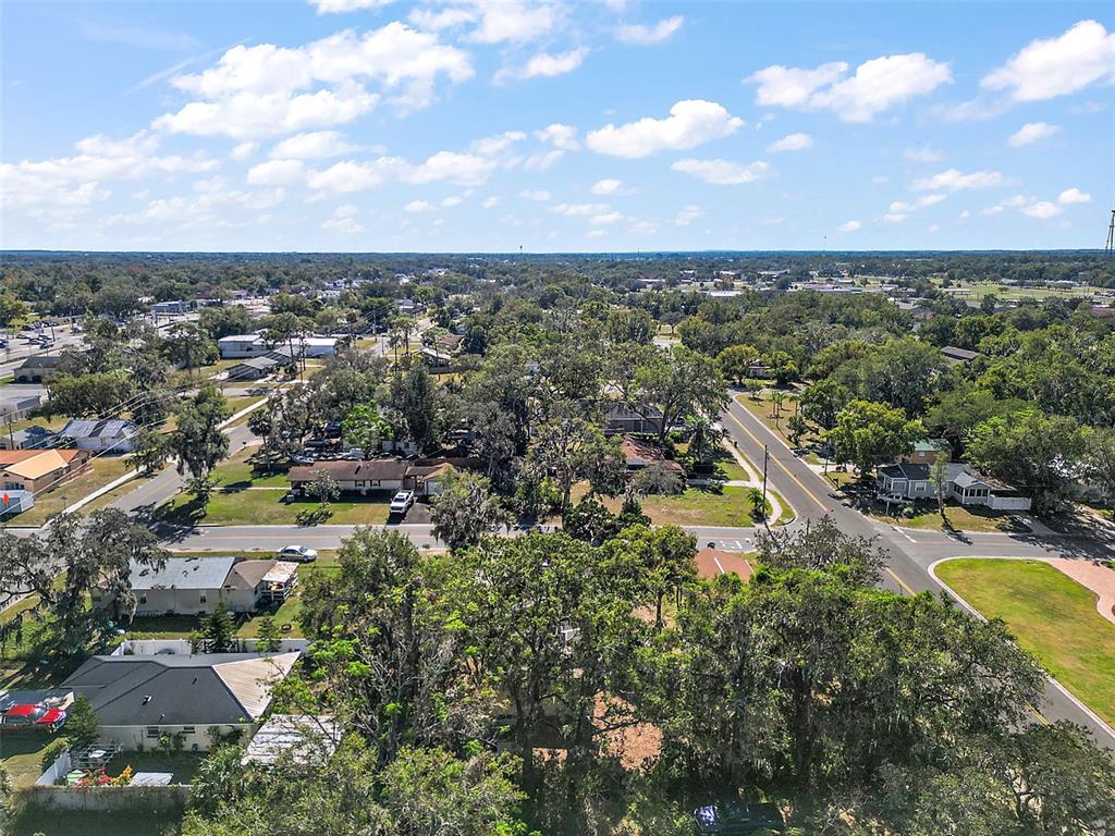 An aerial view shows a residential neighborhood with houses, mature trees, and intersecting roads — 105 W STEVENS AVENUE, EUSTIS, FL