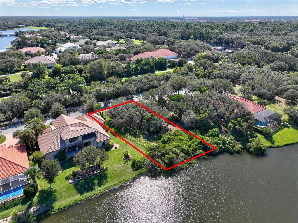 An aerial view shows a vacant, wooded waterfront lot outlined in red next to a house — 40 ATLANTIC PLACE, PALM COAST, FL