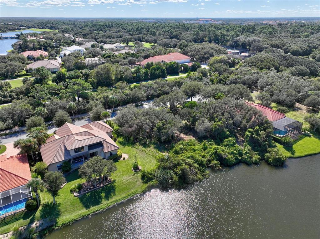 An aerial view shows houses with tiled roofs situated along a lake and surrounded by trees — 40 ATLANTIC PLACE, PALM COAST, FL