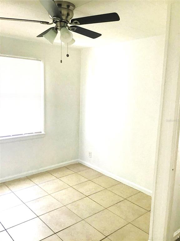 An empty room features white walls, a ceiling fan, and light-colored square floor tiles — 2226 27TH STREET S, ST PETERSBURG, FL
