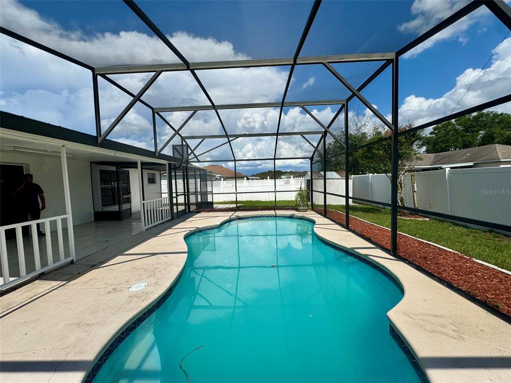 A swimming pool is enclosed by a screened lanai with a concrete deck and fence — 14 YORK COURT, KISSIMMEE, FL