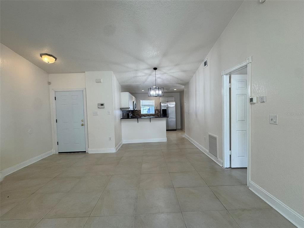 A tiled living area leads to an open kitchen with a breakfast bar and stainless-steel appliances — 14 YORK COURT, KISSIMMEE, FL