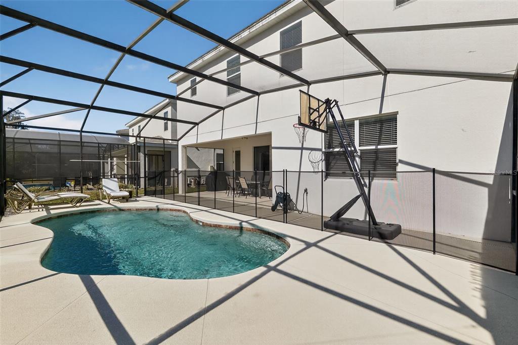 A screened-in patio features a swimming pool, a basketball hoop, and a dining area — 4577 CABELLO LOOP, KISSIMMEE, FL