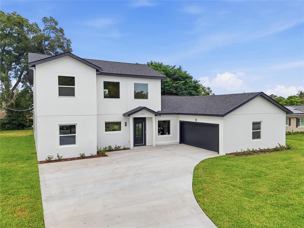 A two-story white house with a dark roof, a front porch, and an attached garage — 351 E WILDMERE AVENUE, LONGWOOD, FL