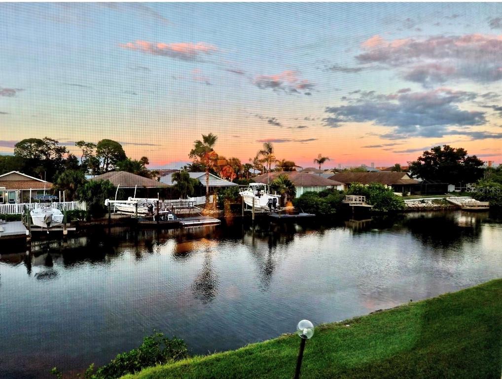 A park bench sits on a grassy lawn overlooking a canal with several docked boats — 4533 MARINE PARKWAY UNIT 204, NEW PORT RICHEY, FL