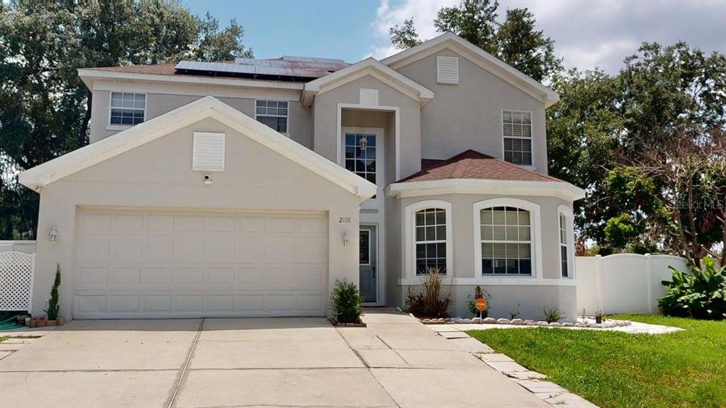 A two-story suburban house with a two-car garage, solar panels, and a light-colored stucco exterior — 2108 ANCIENT OAK DRIVE, OCOEE, FL
