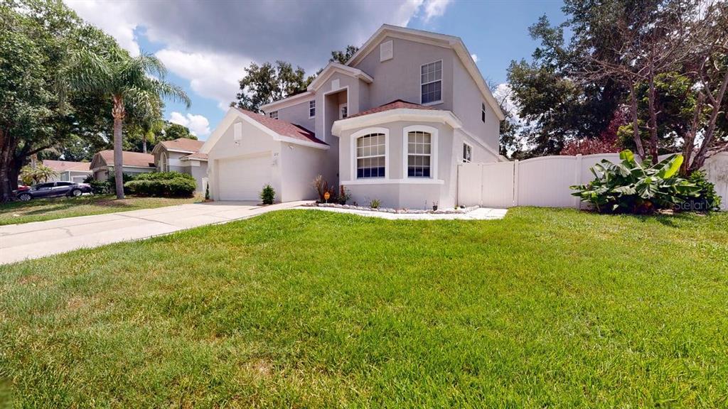 A two-story house with a light-colored exterior, a front garage, and a green lawn — 2108 ANCIENT OAK DRIVE, OCOEE, FL