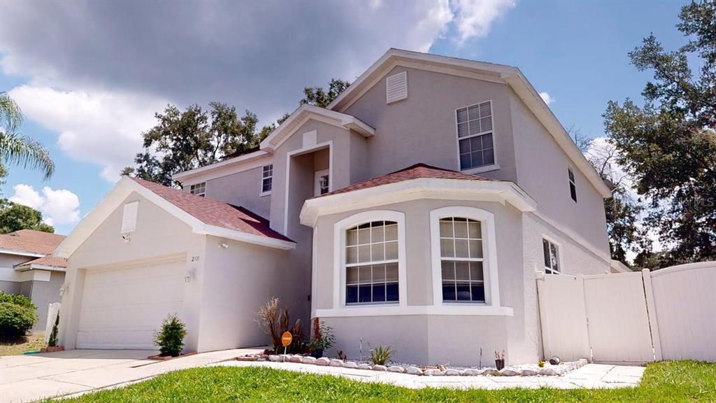 A two-story suburban house with a light gray exterior, a garage, and a front lawn — 2108 ANCIENT OAK DRIVE, OCOEE, FL