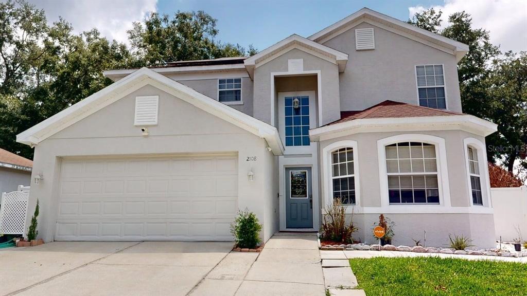 A two-story house with a light-colored stucco exterior, a two-car garage, and a front entrance — 2108 ANCIENT OAK DRIVE, OCOEE, FL