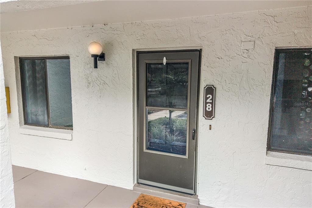 A front exterior view of a residential unit featuring a brown storm door and windows — 4 ESCONDIDO CIRCLE UNIT 28, ALTAMONTE SPRINGS, FL