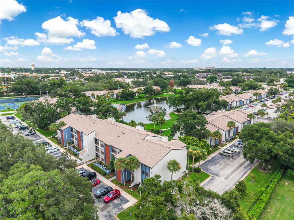 An aerial view shows apartment buildings surrounding a central pond with adjacent parking lots — 4 ESCONDIDO CIRCLE UNIT 28, ALTAMONTE SPRINGS, FL