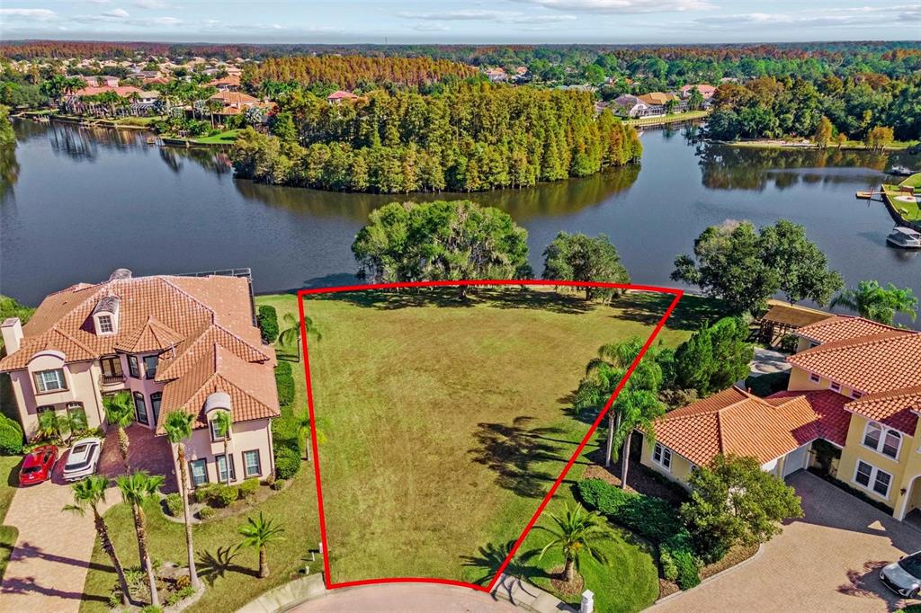 An aerial view shows a vacant waterfront lot outlined in red between two large houses — 17903 BIMINI ISLE COURT, TAMPA, FL