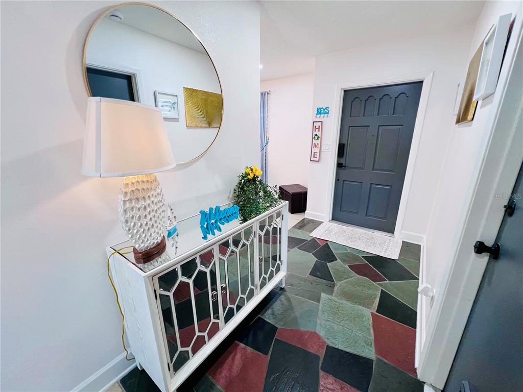 An entryway features a mirrored console table, a round wall mirror, and flagstone flooring — 13607 101ST TERRACE, SEMINOLE, FL