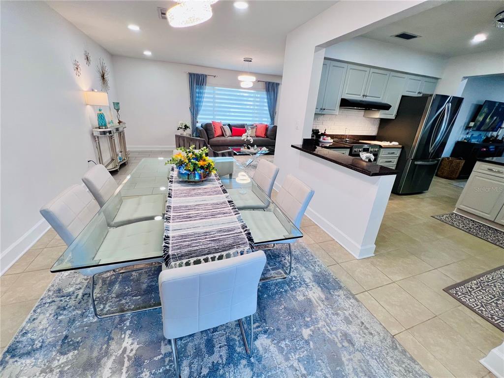 A dining area with a glass table and white chairs opens to a kitchen — 13607 101ST TERRACE, SEMINOLE, FL